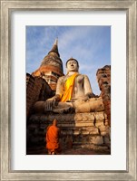 Framed Monk praying in front of a statue of Buddha