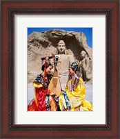 Framed Two girls in traditional costumes in front of the Buddha Statue, China