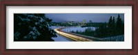 Framed Autumobile lights on busy street, distant city lights, frozen Westchester Lagoon, Anchorage, Alaska, USA.
