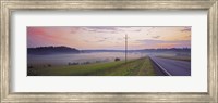 Framed Country road and telephone lines splitting farmlands at dawn, Finland