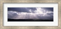 Framed Sunbeams radiating through dark clouds over rolling hills, Dartmoor, Devon, England