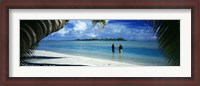 Framed Rear view of two native teenage girls in lagoon, framed by palm tree, Aitutaki, Cook Islands.