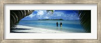 Framed Rear view of two native teenage girls in lagoon, framed by palm tree, Aitutaki, Cook Islands.