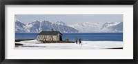 Framed Two hikers standing on the beach near a hunting cabin, Bellsund, Spitsbergen, Svalbard Islands, Norway