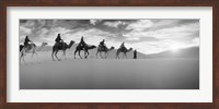 Framed Tourists riding camels through the Sahara Desert landscape led by a Berber man, Morocco (black and white)