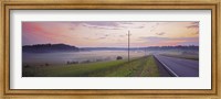 Framed Country road and telephone lines splitting farmlands at dawn, Finland