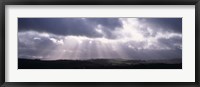 Framed Sunbeams radiating through dark clouds over rolling hills, Dartmoor, Devon, England