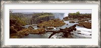 Framed Log on the rocks at the top of the Victoria Falls with Victoria Falls Bridge in the background, Zimbabwe