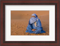 Framed Veiled Tuareg man sitting cross-legged on the sand, Erg Chebbi, Morocco