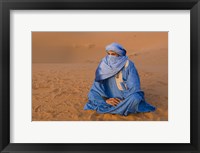 Framed Veiled Tuareg man sitting cross-legged on the sand, Erg Chebbi, Morocco