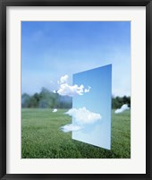 Framed White clouds passing through a pale blue horizontal of sky with green grass, trees and sky in the distance