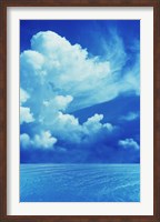 Framed White clouds in dark blue sky over rippling water