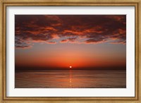 Framed layer of clouds is lit by the rising sun over Rio de la Plata, Buenos Aires, Argentina