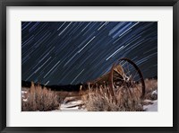 Framed Abandoned farm equipment against a backdrop of star trails