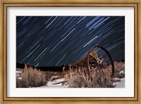 Framed Abandoned farm equipment against a backdrop of star trails