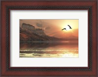 Framed Two Bald Eagles fly along a mountainous coastline at sunset