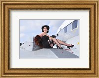 Framed Glamorous woman in 1940's style attire sitting on a vintage aircraft