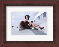 Framed Glamorous woman in 1940's style attire sitting on a vintage aircraft