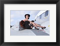 Framed Glamorous woman in 1940's style attire sitting on a vintage aircraft