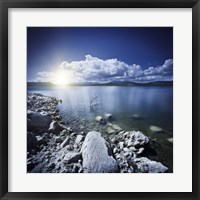 Framed Tranquil lake and rocky shore with sun over horizon, Sardinia, Italy