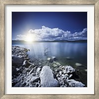 Framed Tranquil lake and rocky shore with sun over horizon, Sardinia, Italy