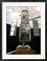 Framed Space Shuttle Atlantis' arm lifts the Hubble Space Telescope from the cargo bay