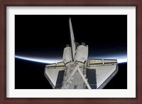 Framed Space Shuttle Discovery Intersecting the Thin line of Earth's Atmosphere, while Docked with the International Space Station
