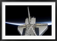 Framed Space Shuttle Discovery Intersecting the Thin line of Earth's Atmosphere, while Docked with the International Space Station