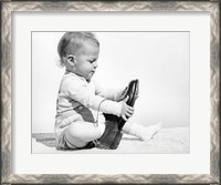 Framed 1960s Baby Boy Trying To Put On Man'S Shoe