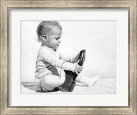 Framed 1960s Baby Boy Trying To Put On Man'S Shoe